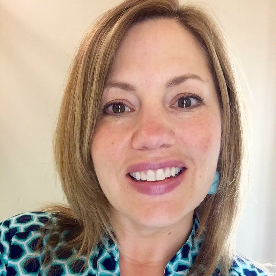 Headshot of a smiling Caucasian woman in a patterned top.