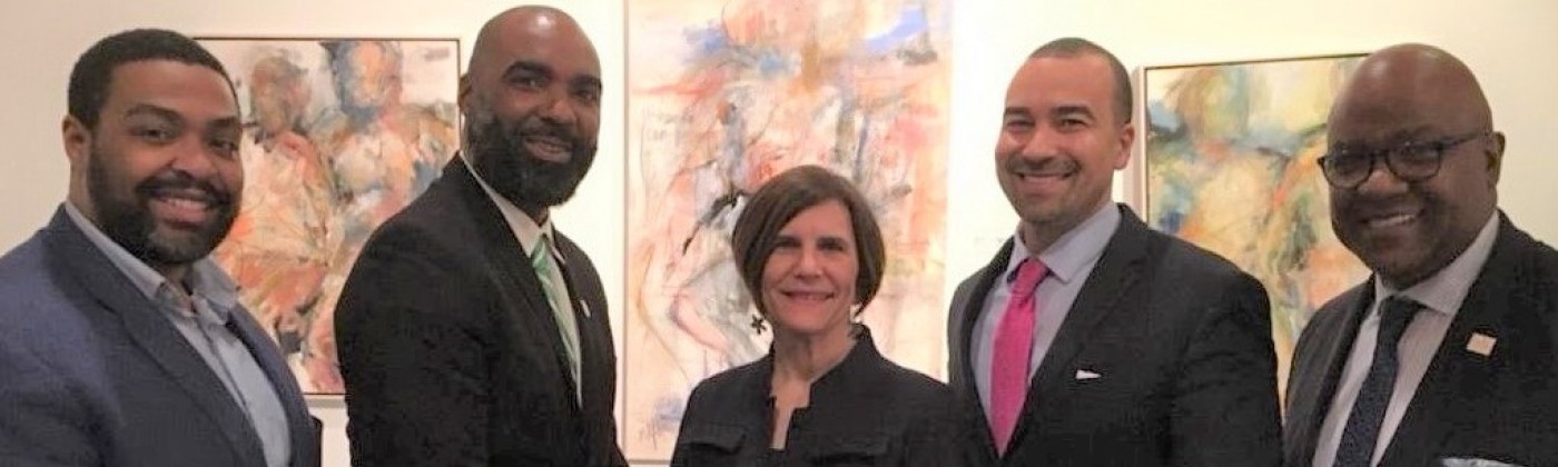 Four men of color and one Caucasian woman, all in suits, posing for a picture.