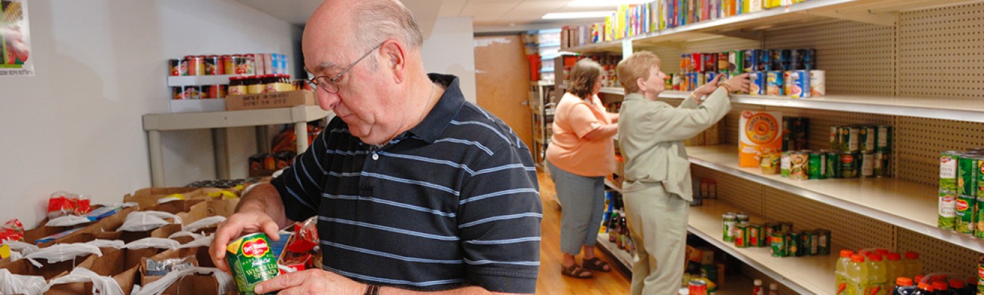 Three people stocking a food pantry's shelves.