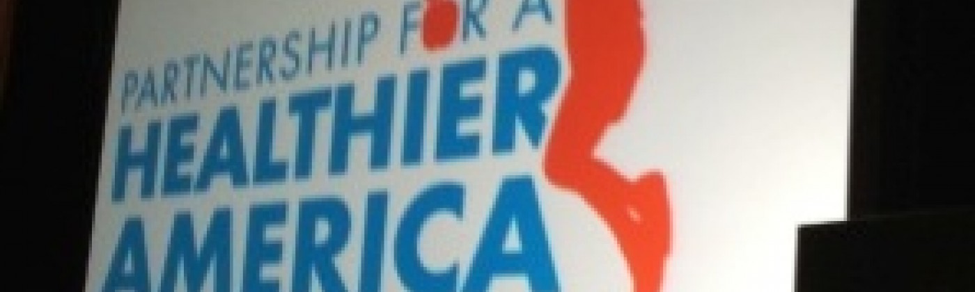 Projection screen that displays a silhouette of a child jumping with the words, "Partnership for a Healthier America."
