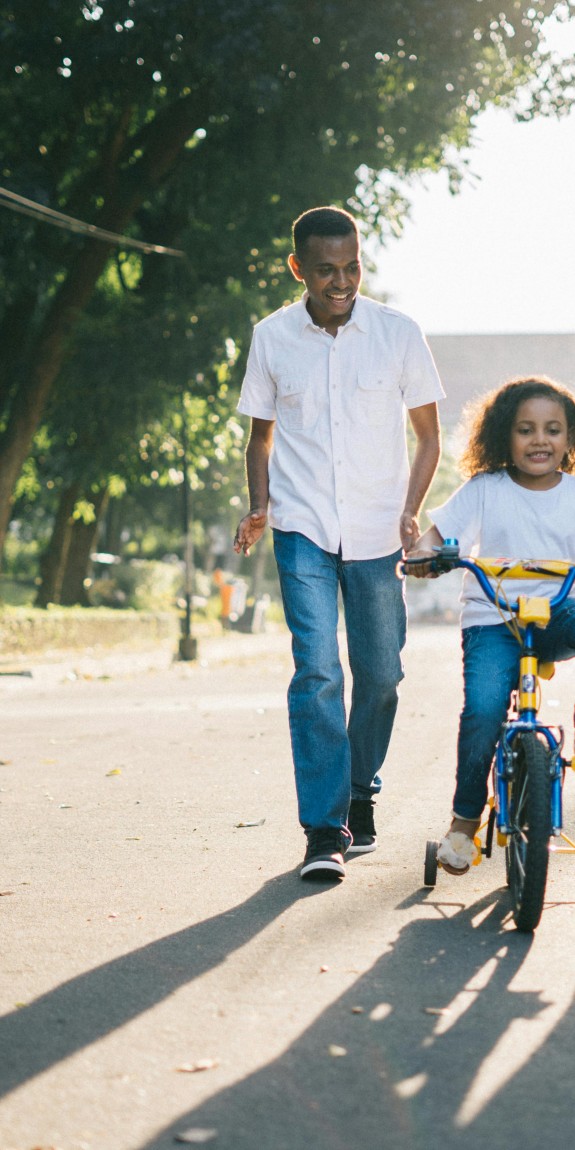 image of family helping child learn to ride a bike