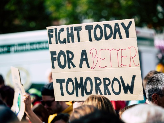 Person holding a sign that says "Fight today for a better tomorrow."