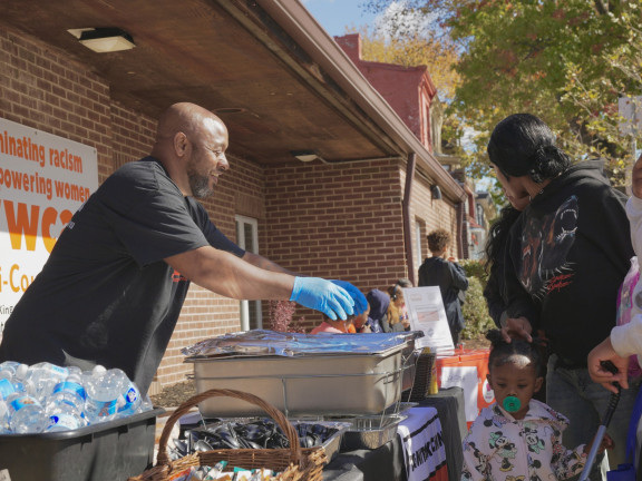 A man hands out catered food at a community event.