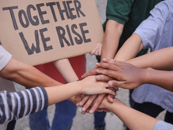 An image of multiple hands stacked on top of each other to express solidarity.