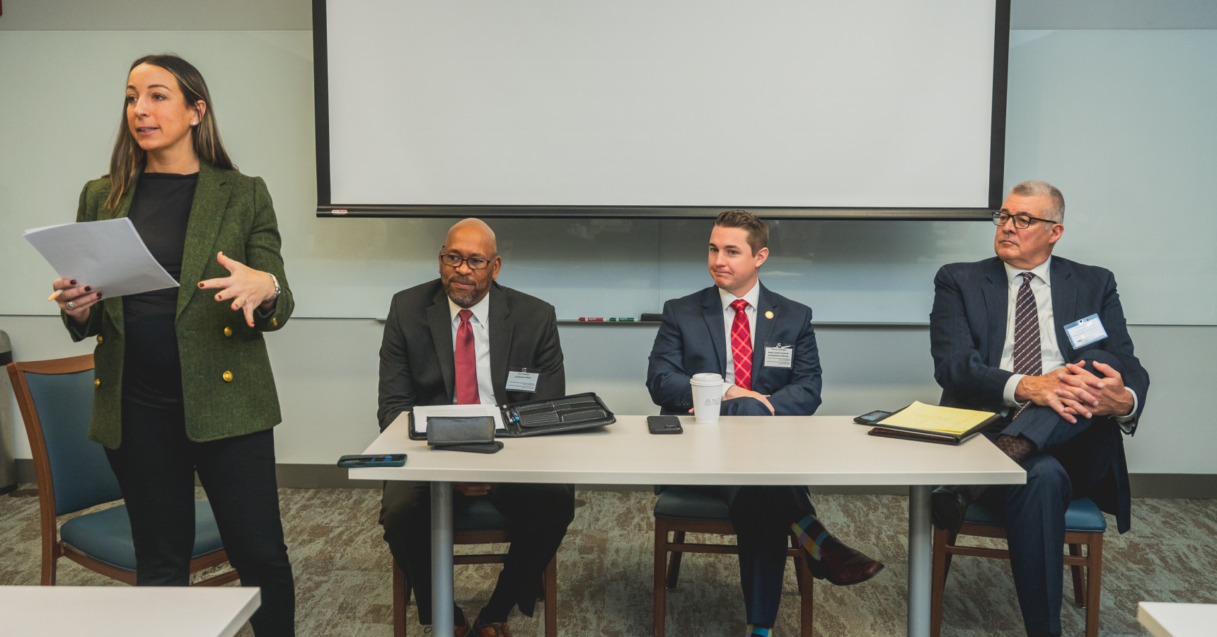 three men at a table and a woman talking