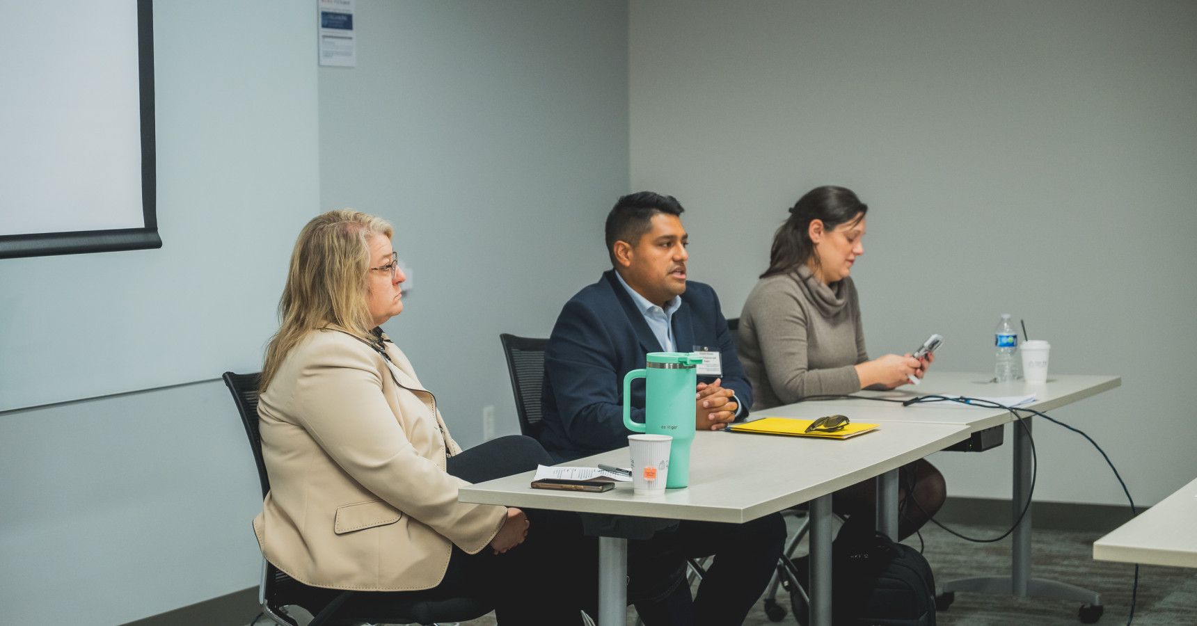 Three people talking at a long table to an audience.