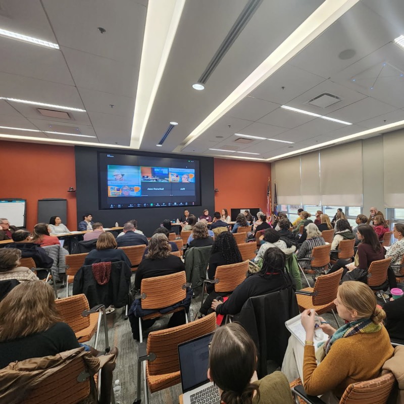 An audience of about 80 people listening to community representatives speak.