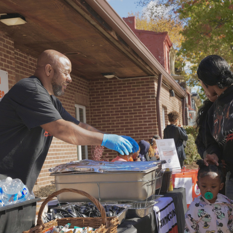A man hands out catered food at a community event.