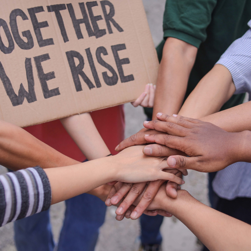 An image of multiple hands stacked on top of each other to express solidarity.