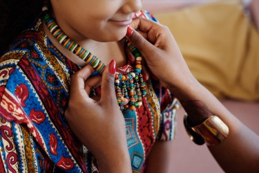 woman putting beaded necklace around child's neck during kwanzaa celebration