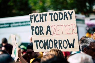 A person holding a sign in a crowd that says "Fight today for a better tomorrow."