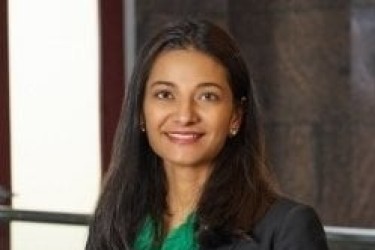 image of smiling woman with shoulder length brown hair, wearing a black blazer and a green blouse