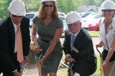 Six people participating in a ground breaking ceremony with shovels.