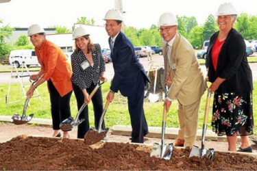 Five people with shovels participating in a groundbreaking ceremony.