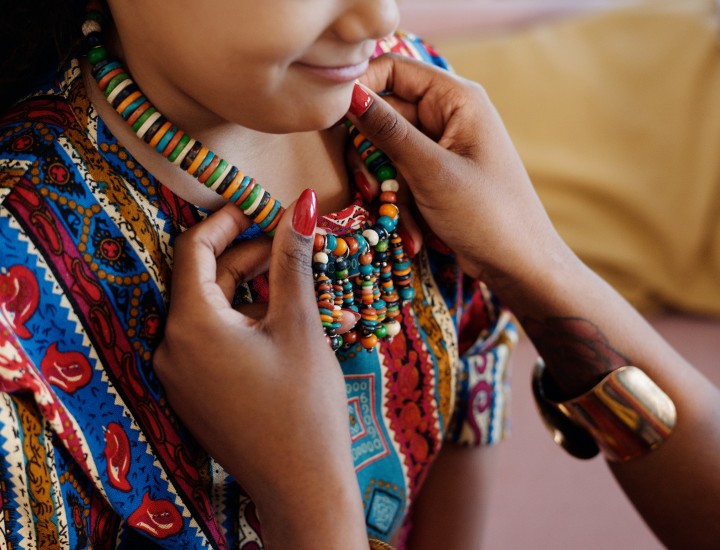 woman putting beaded necklace around child's neck during kwanzaa celebration