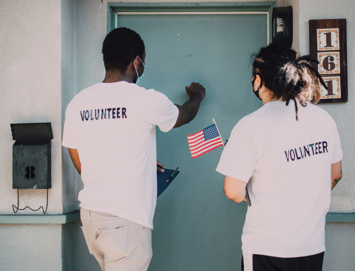Two volunteers knocking on a blue door. 